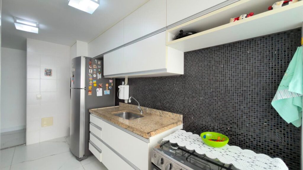 Cozinha com bancada em granito, cooktop e revestimento em pastilha